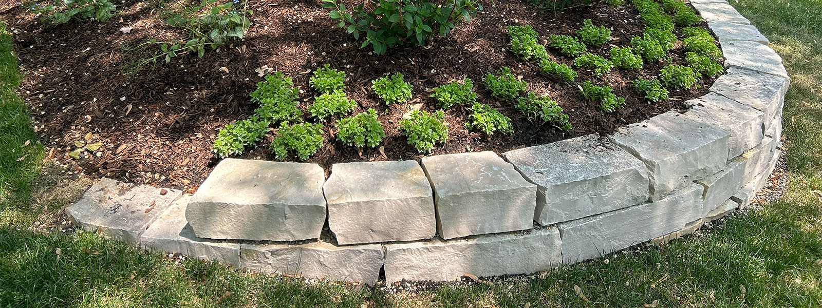 Curved stone retaining wall garden bed